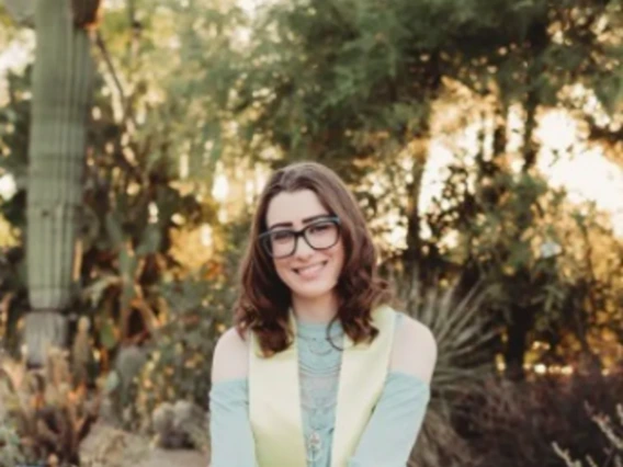 Courtney smiles at sunset in front of a cactus garden.