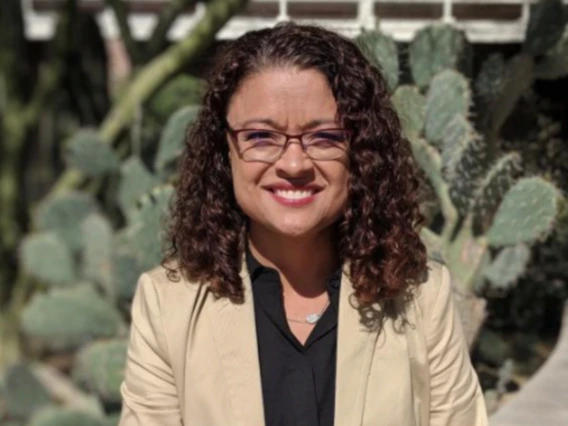 Kimberly Sierra smiles at the camera in a tan blazer, and black shirt.