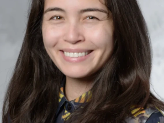Raine Ikagawa wears a long-sleeve button shirt with a bee design. She smiles at the camera.